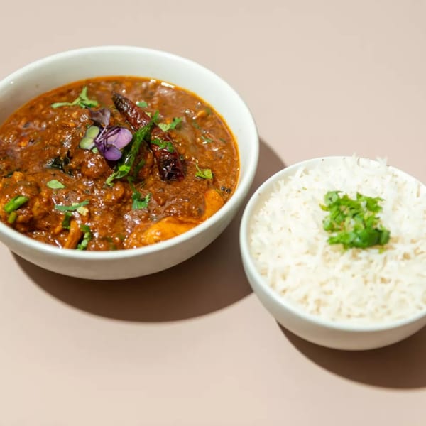 A bowl of Haldi Fine Indian Cuisine's chicken curry with a side of white rice.